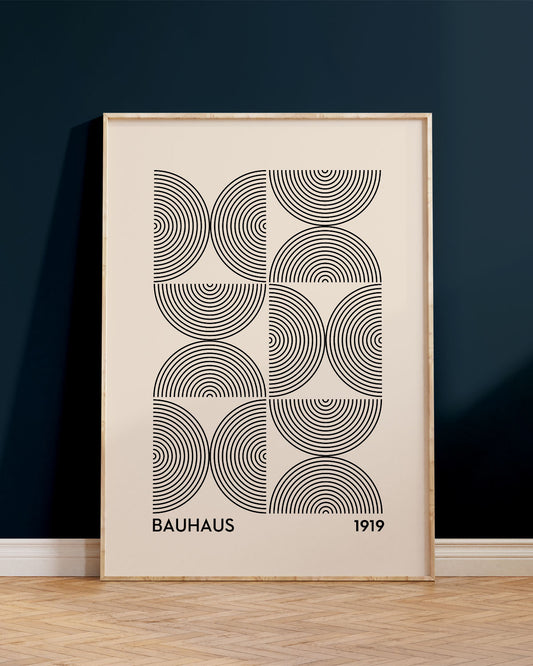 Innrammað Bauhaus veggspjald, upp við dökkbláan vegg, ofan á viðargólfi