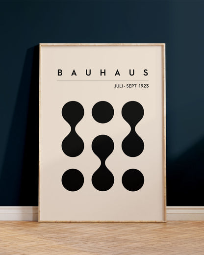 Innrammað Bauhaus plakat, upp við dökkbláan vegg, ofan á viðar´gólfi