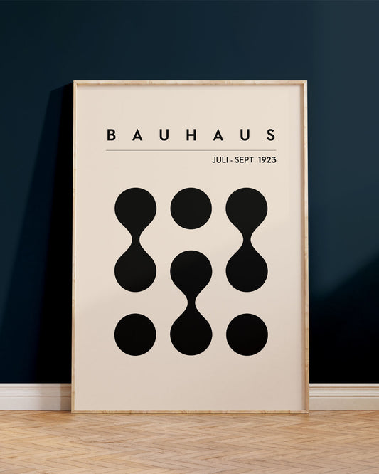 Innrammað Bauhaus plakat, upp við dökkbláan vegg, ofan á viðar´gólfi