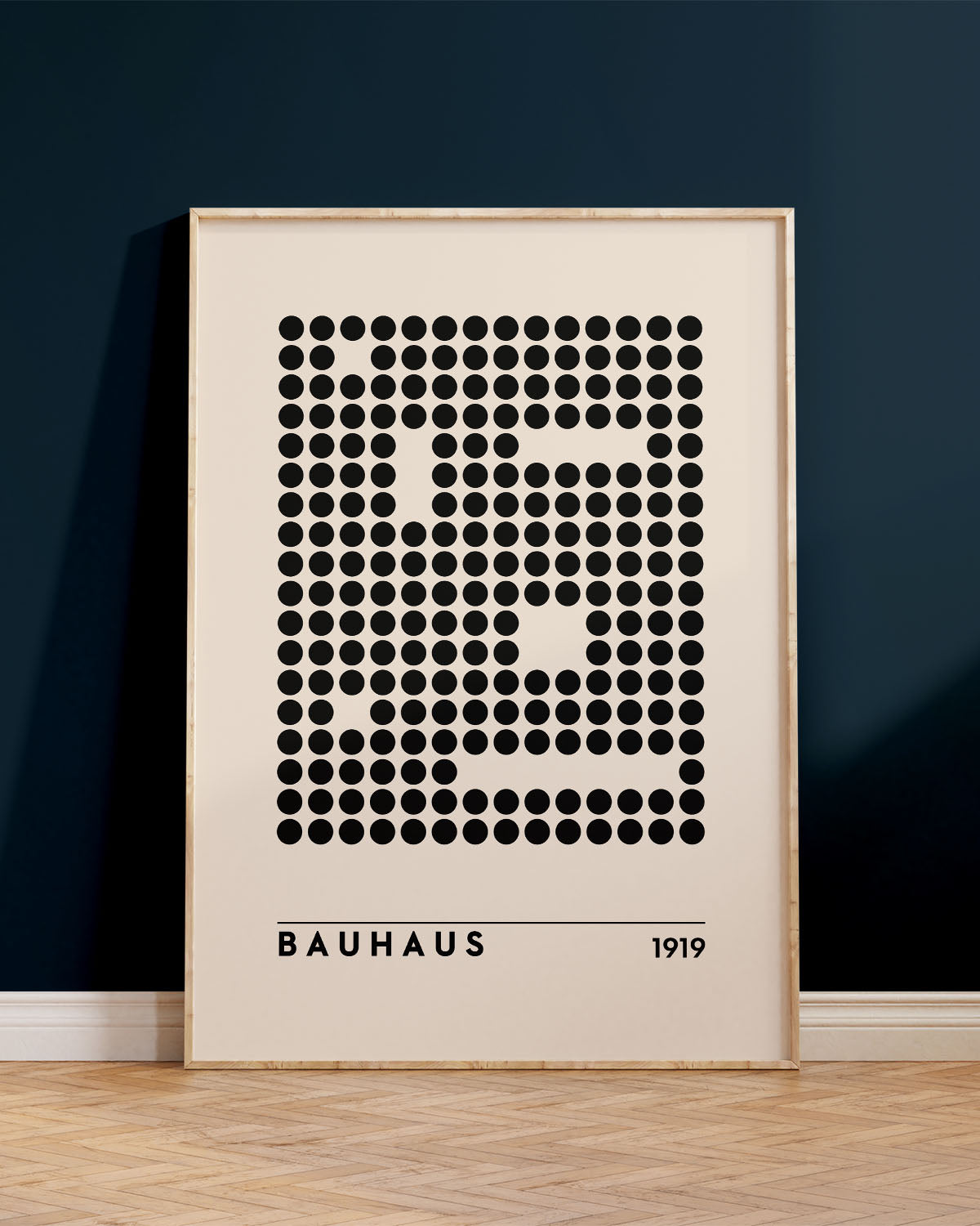 Innrammað Bauhaus veggspjald, uppvið bláan vegg, ofan á brúnu viðargólfi.