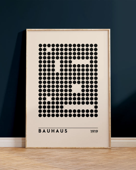 Innrammað Bauhaus veggspjald, uppvið bláan vegg, ofan á brúnu viðargólfi.