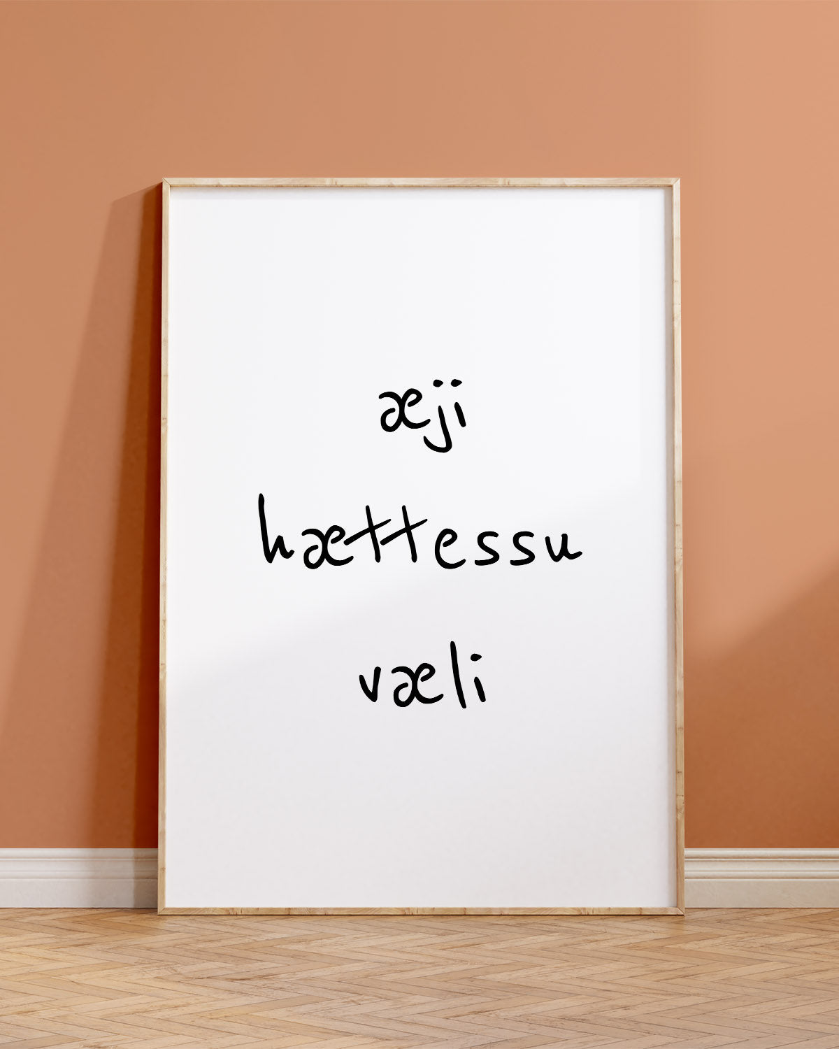 Veggspjald í ramma upp við brúnappelsínugulan vegg með textanum: æji hættessu væli