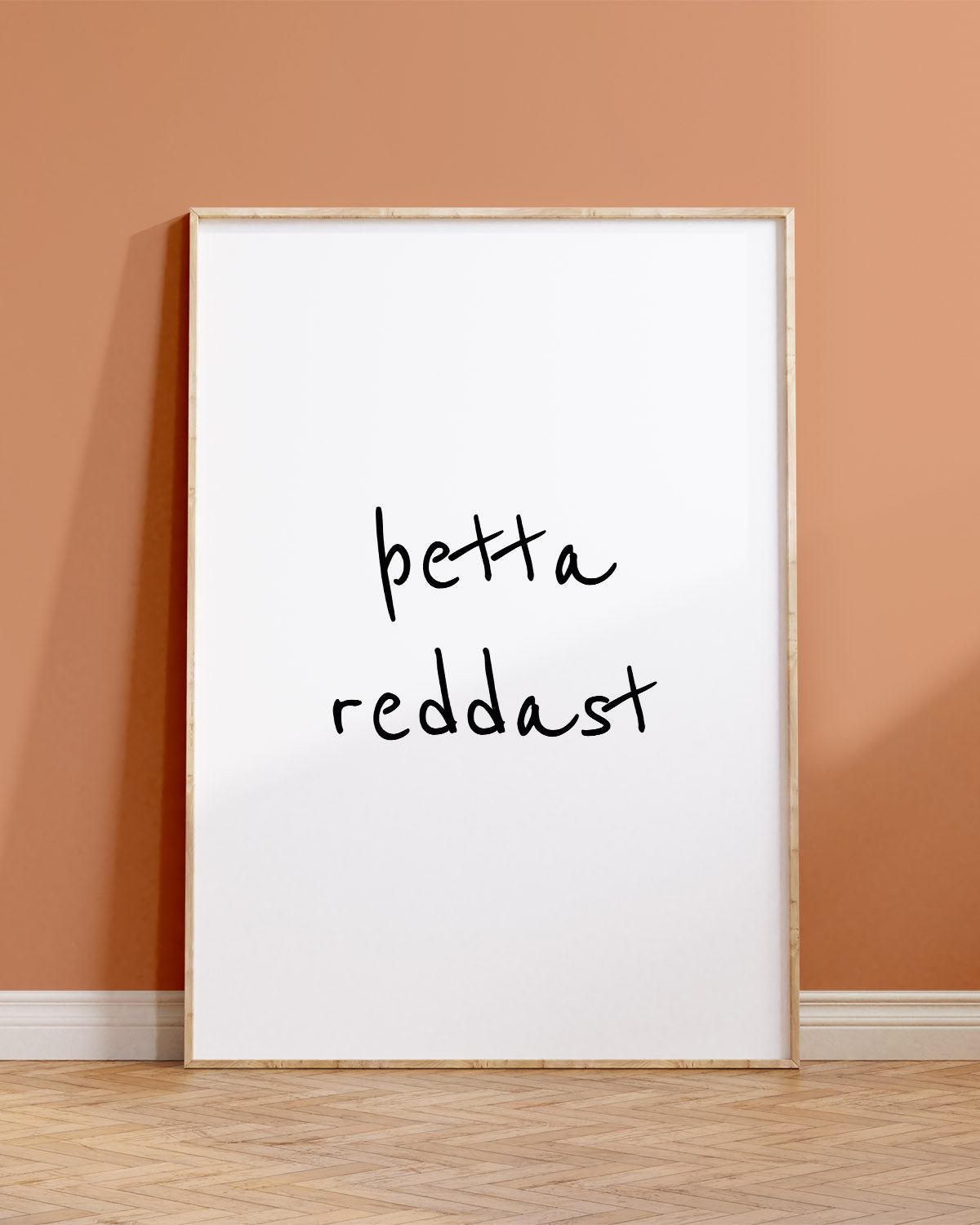 Veggspjald í ramma upp við brúnappelsínugulan vegg með textanum: þetta reddast