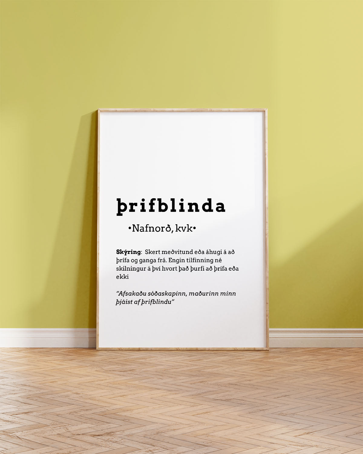 Innrammað veggspjald upp við gulan vegg, ofan á brúnu viðargólfi.  á veggspjaldinu stendur: Þrifblinda, ásamt frekari skýringum á orðinu.