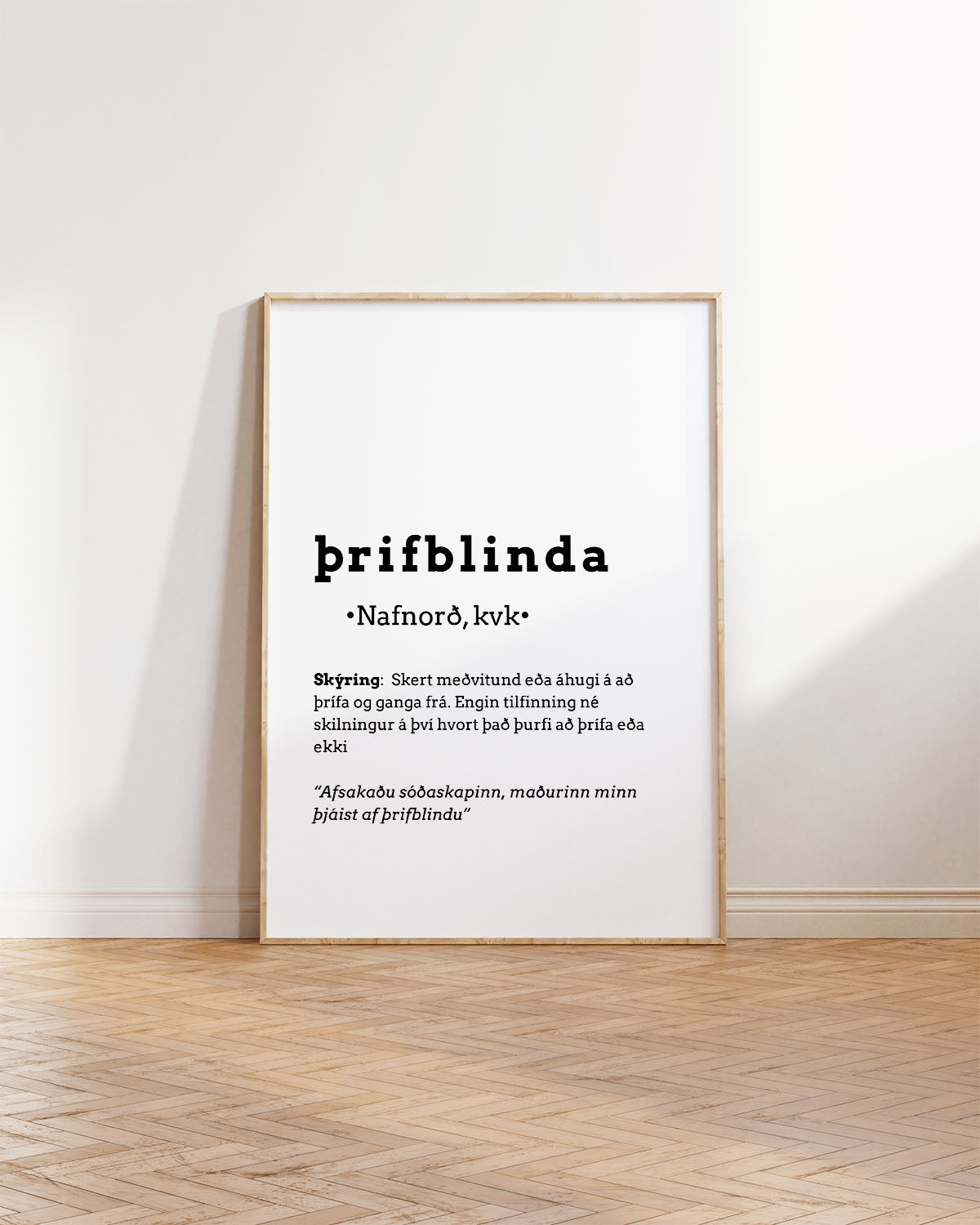 Innrammað veggspjald upp við hvítan vegg, ofan á brúnu viðargólfi.  á veggspjaldinu stendur: Þrifblinda, ásamt frekari skýringum á orðinu.